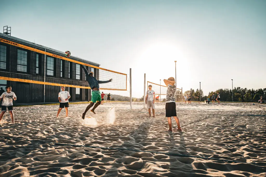 Kinder spielen Beach-Volleyball im sommerlichen Abendlicht.