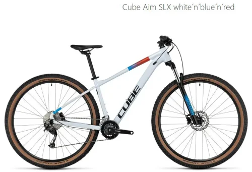 Ein Mountainbike mit einem weißen Rahmen, blauen und roten Akzenten. Es hat 29-Zoll-Räder mit braunen Seitenwänden, Scheibenbremsen und eine Federgabel. Der Markenname "CUBE" ist auf dem Rahmen sichtbar.